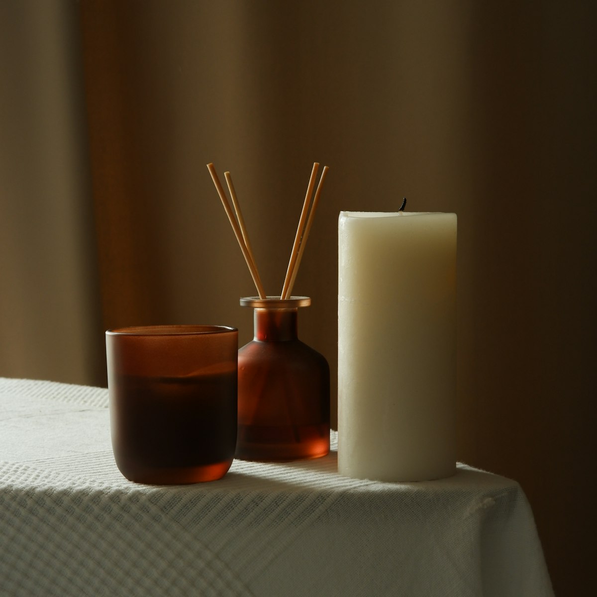 A single lit candle in a ceramic holder on warm wood