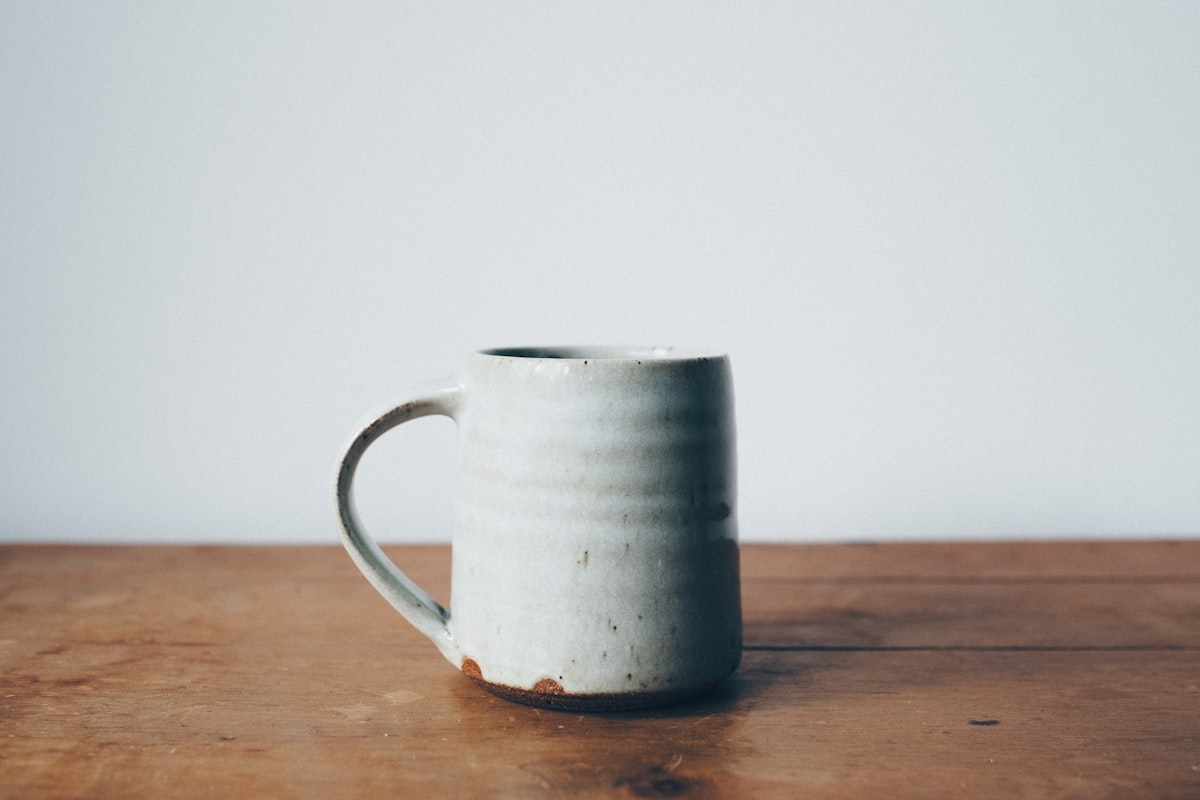 A ceramic mug of coffee on a warm wooden table in soft morning light
